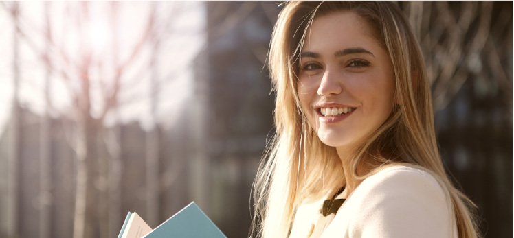 Chica rubia sonriendo con un libro